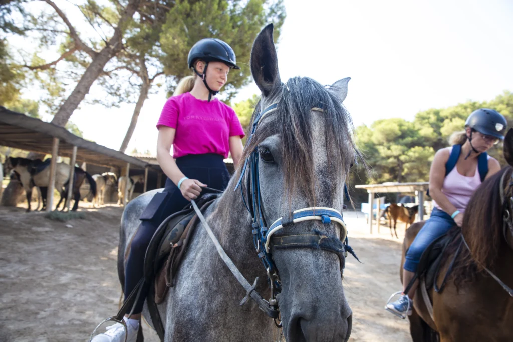 Family horse riding experience in Alcudia, Mallorca, with children and adults riding calm horses at a countryside ranch.